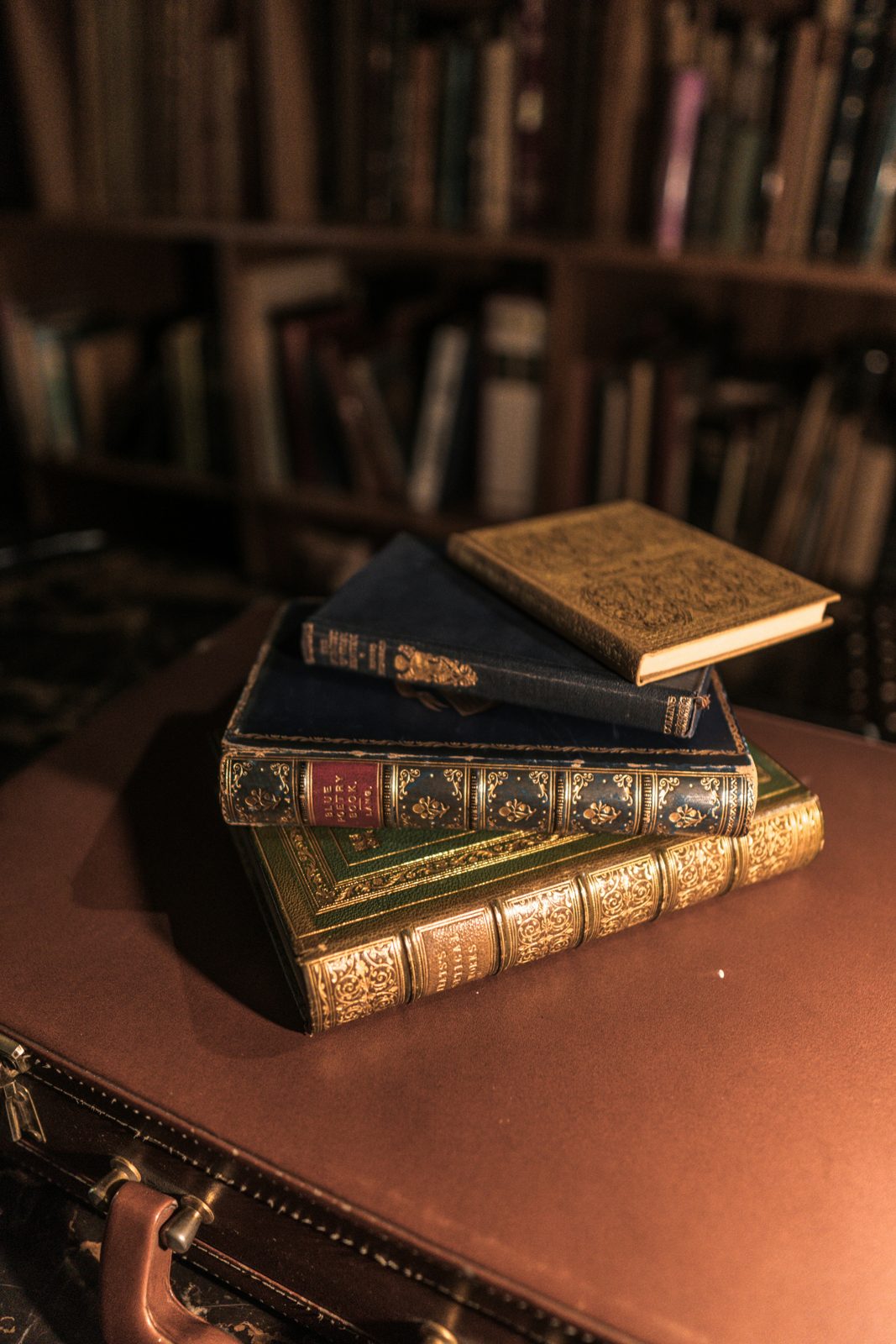 Pile de livres anciens relies en cuir avec dorures, poses sur un bureau en cuir - ou vendre un livre ancien